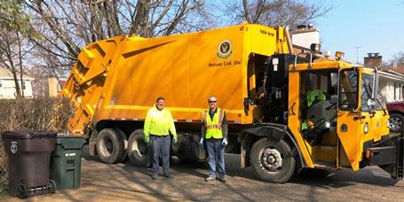 Refuse collection crew in front of vehicle