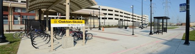 Image of front of train station, with bikes in a bike rack and sign with text Oakton Station